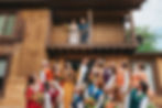 Married Couple looking down from balcony at rainbow colored wedding party.