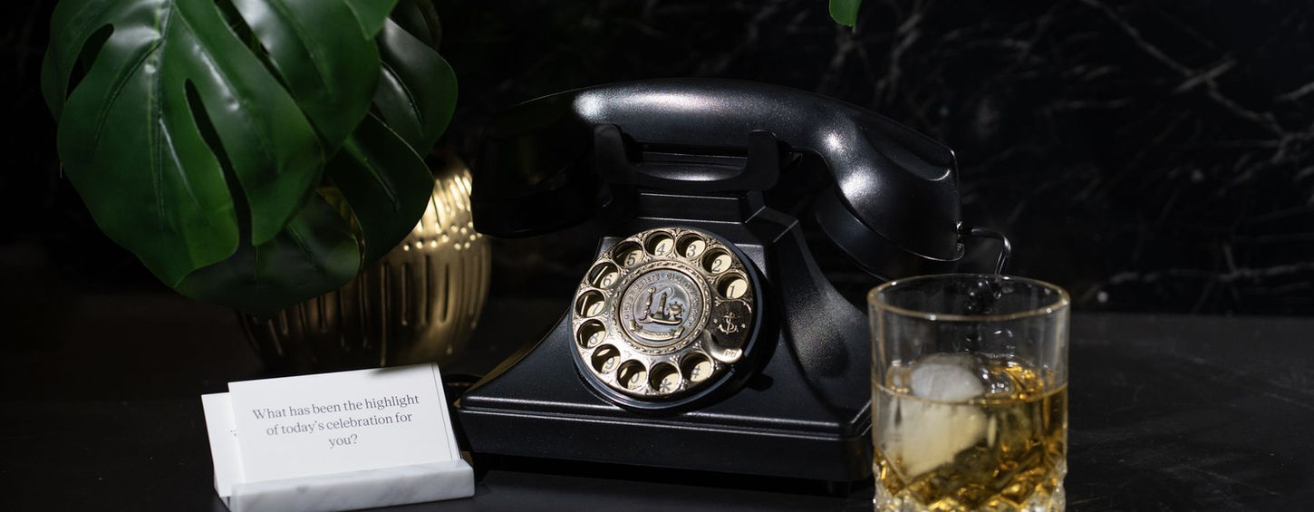 Black vintage-style audio guestbook, glass of whiskey, and a card with text: What has been the highlight of today celebration for you?