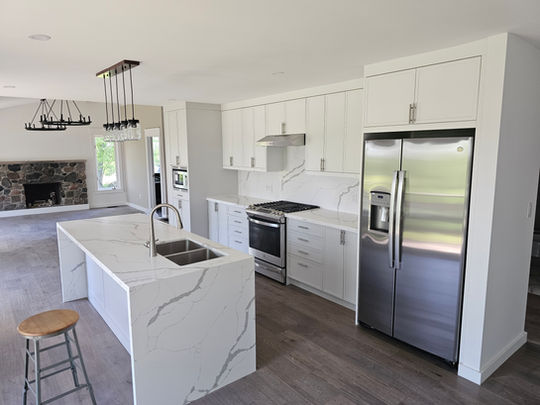 Open-concept kitchen with white shaker cabinets, quartz waterfall island, and stainless steel appliances designed by GTA Kitchen Depot Toronto.