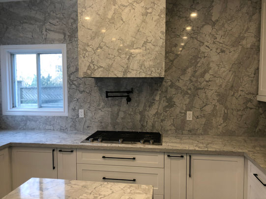 Kitchen with full-height marble quartz backsplash and integrated hood wall by GTA Kitchen Depot Vaughan.