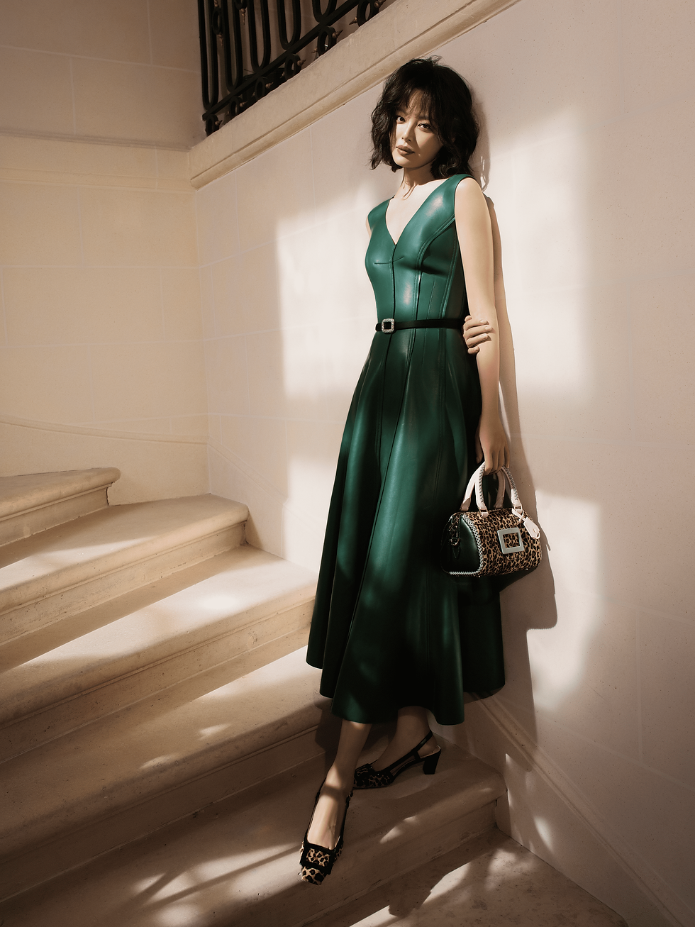 辛芷蕾穿深綠皮革洋裝,搭配Belle Vivier 45 Slingback Pump 豹紋方扣高跟鞋於階梯間