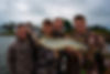 Four anglers proudly display a large pike caught during a fishing trip