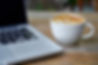 A MacBook with a latte beside it