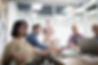 A group of people in a business meeting room looking towards a speaker