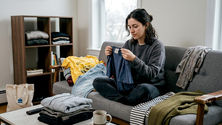 Young adult sorting clothes on sofa