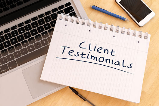 A notepad with the words 'Client Testimonials' resting on a laptop.