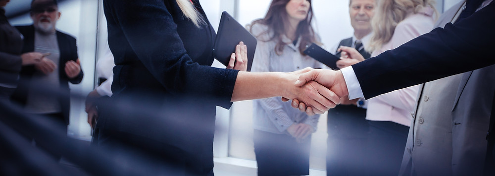 Two salespeople shaking hands to close a deal.