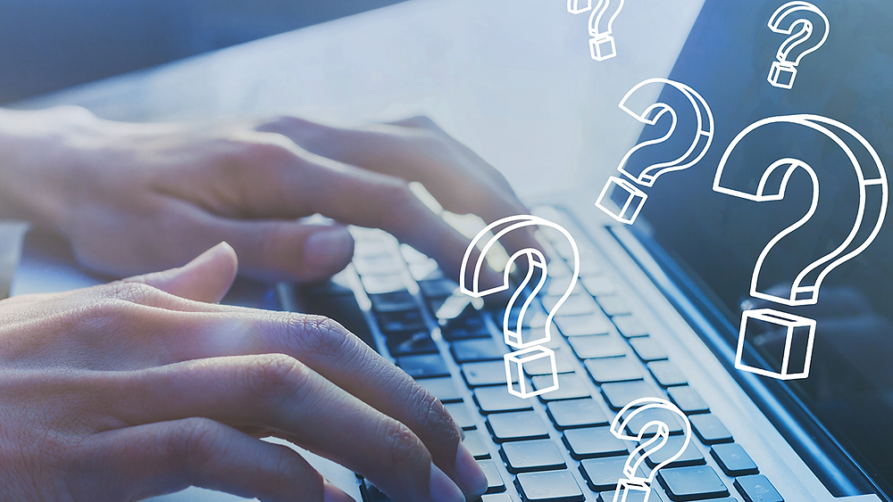 Man typing on computer with question marks surrounding him