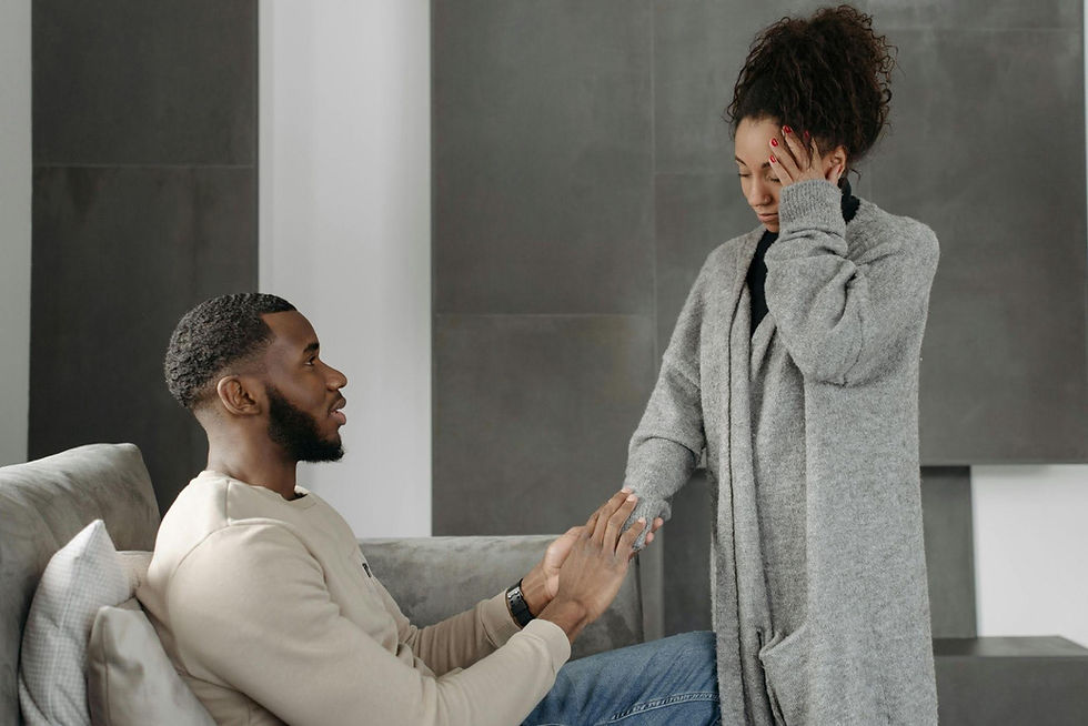 A woman stands emotionally overwhelmed while her partner gently reaches toward her in support, reflecting the quiet impact burnout and emotional exhaustion can have on relationships at home.