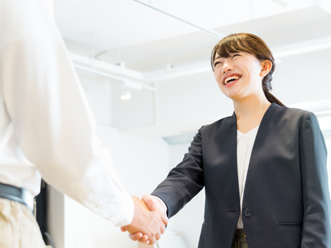 企業の採用担当者と外国人求職者が笑顔で握手を交わし、採用・雇用契約をイメージするビジネスシーン