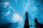 Ice climber rappelling ice wall to team of climbers below