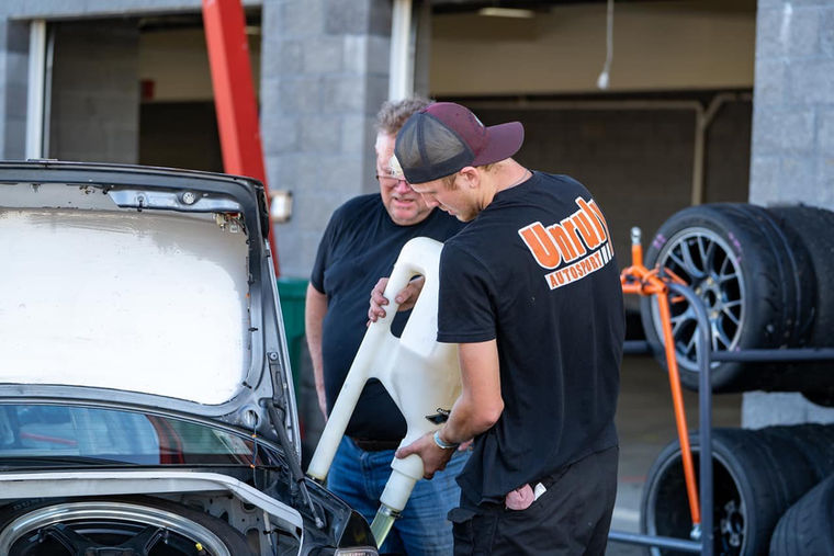 Man in Unruly Autosport team shirt filling a car with fuel.