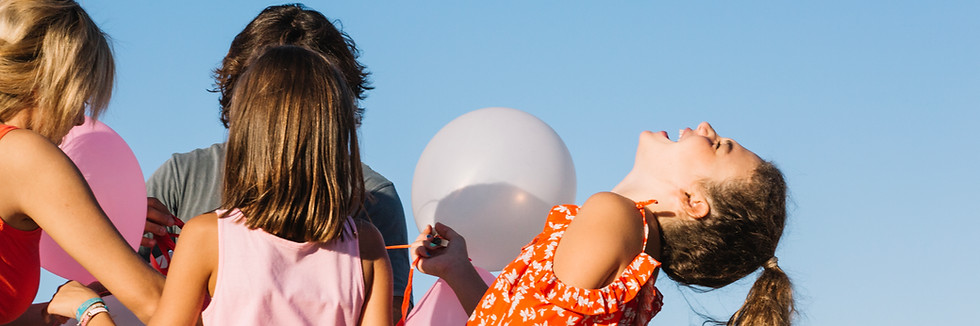laughing-girl-holding-balloons-with-family.jpg