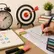 Student solving an SSC exam OMR sheet with a stopwatch, target board, study books, and stationery on a study desk, representing speed and accuracy in exam preparation.