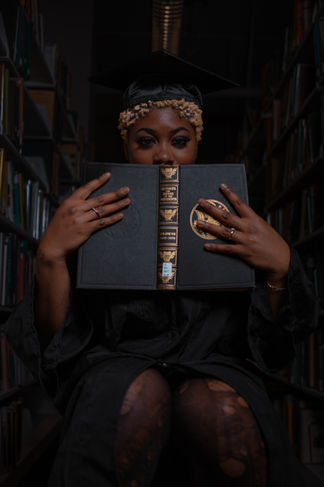 a woman in a graduation cap and gown is holding a book that says encyclopedia britannica