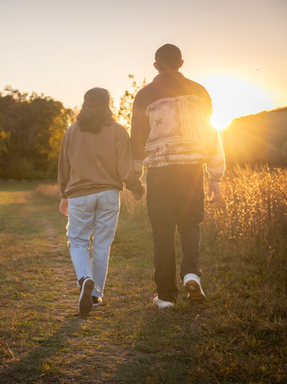 a man and a woman are walking down a dirt path holding hands