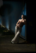 Dramatic low-key lighting portrait of a model leaning against a blue container at an Oahu photography workshop.
