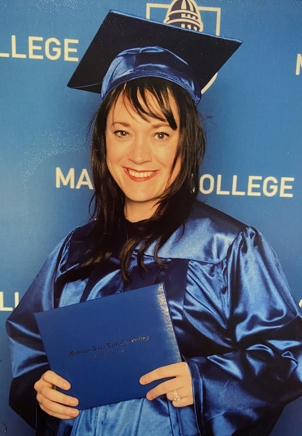 Jessi in a blue cap and gown hugging her husband on graduation day, both smiling