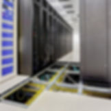 Eye-level view of a raised access floor panel with server racks in the background