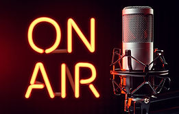 Professional silver microphone with bright orange illuminated ON AIR neon sign.jpg