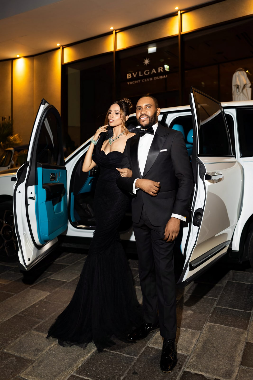 A black-tie arrival beside a vehicle at night
