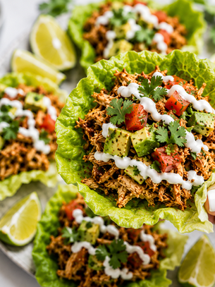 Fresh and flavorful setup for a game day snack: shredded chicken, crisp lettuce, zesty lime, creamy avocado, and more delicious ingredients ready to assemble into tasty bites.