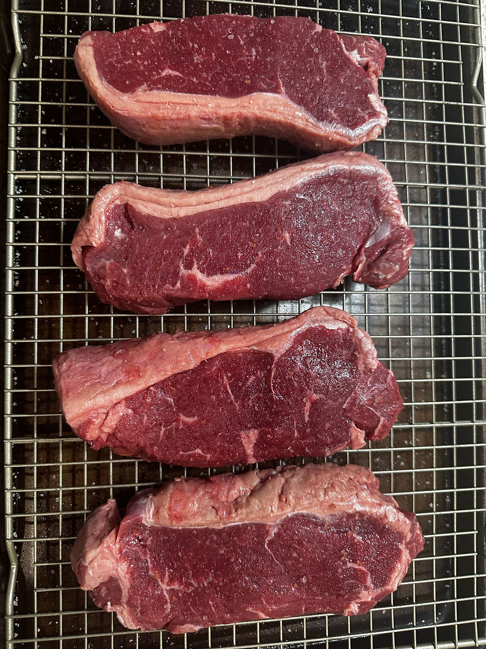 Thick steaks neatly arranged on a wire rack, marinated in salt to enhance flavor and tenderness.