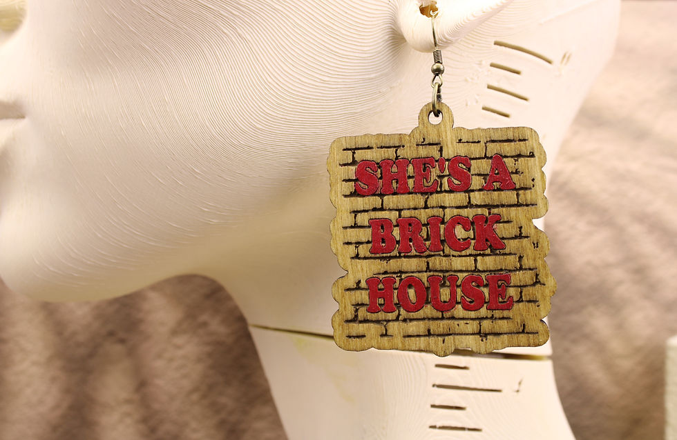 Wooden earring with 'She's a Brick House' text on a mannequin.
