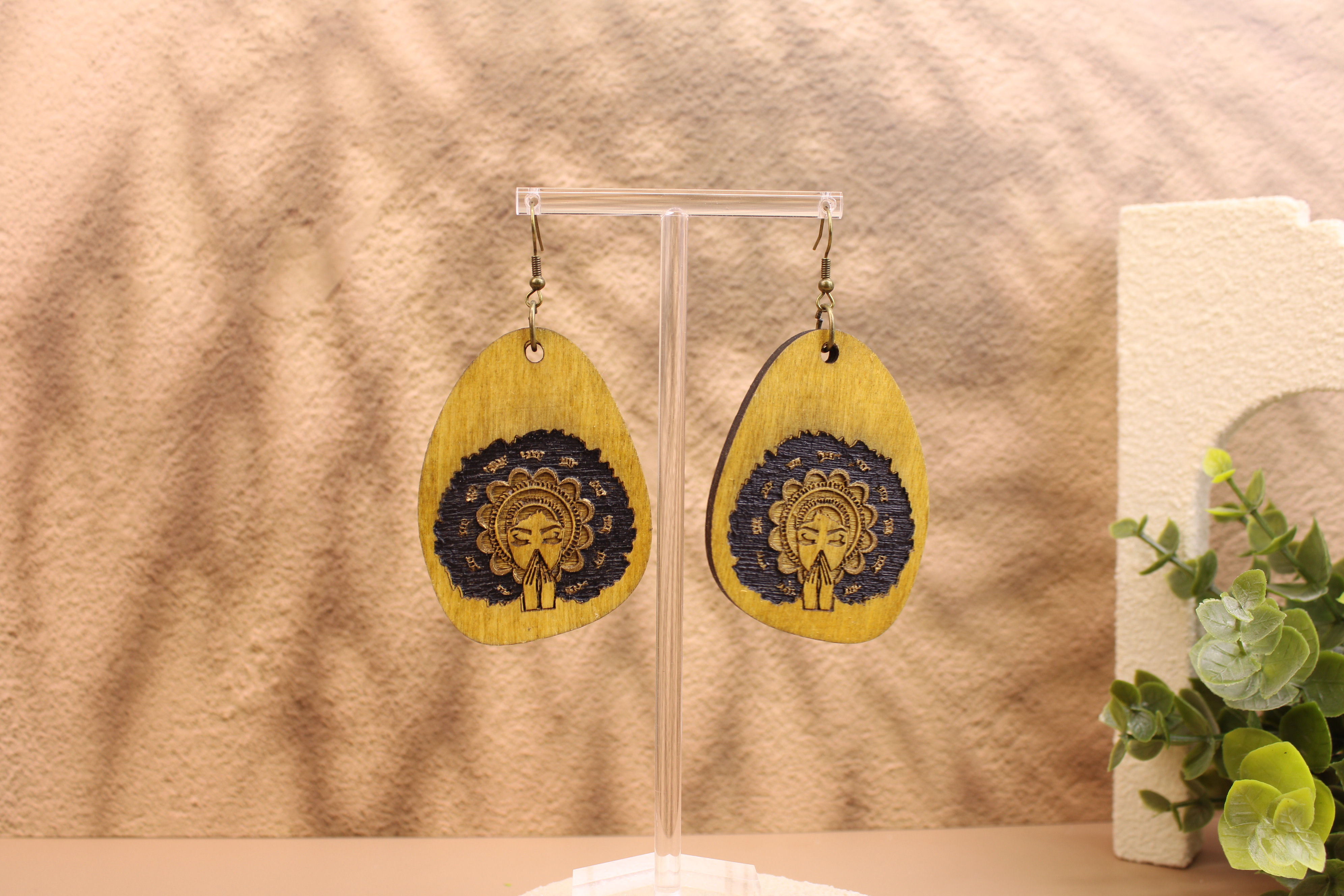Sacred Crown Queen teardrop earrings on a display stand.