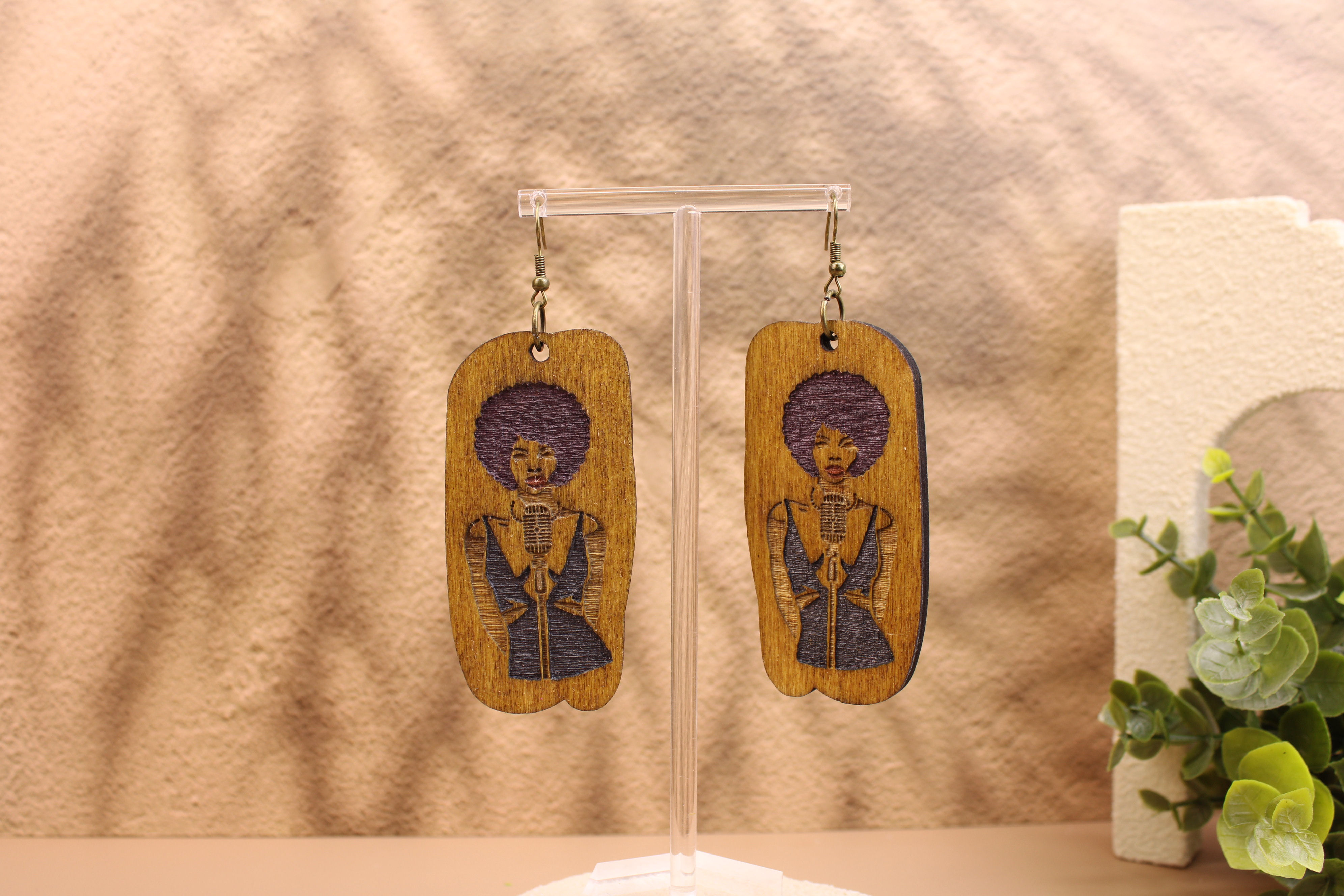 Purple Afro Songstress wood earrings on a stand