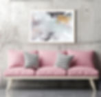 Obraz na stěně v obýváku. Abstraktní obraz v rámu nad růžovou pohovkou.
