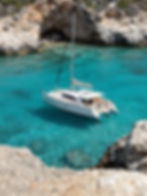 Catamaran sailing boat in clear turquoise cove