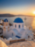 White church with blue domes at sunset, sailing boat on sea