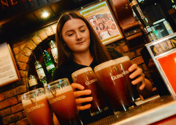 Staff member serving freshly poured pints of Guinness behind the bar at Charlie's Bar in Enniskillen.