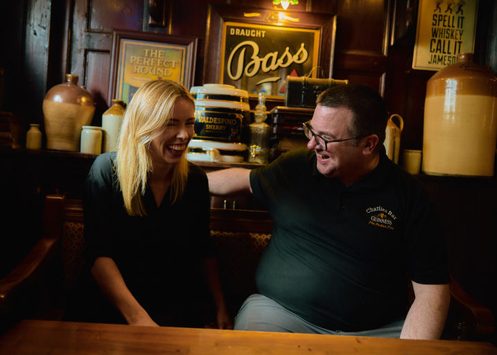 Two staff members enjoying  conversation inside Charlie's Bar in Enniskillen, surrounded by traditional Irish pub décor.