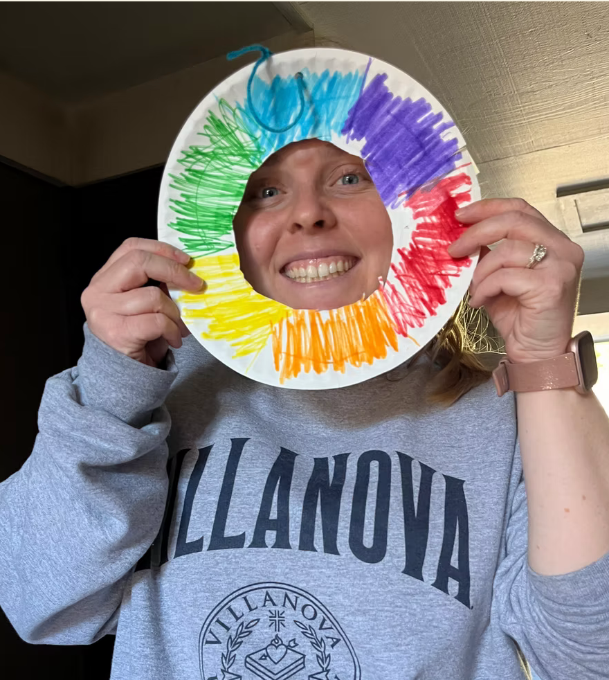 young adult showing off an arts and crafts project with a big smile