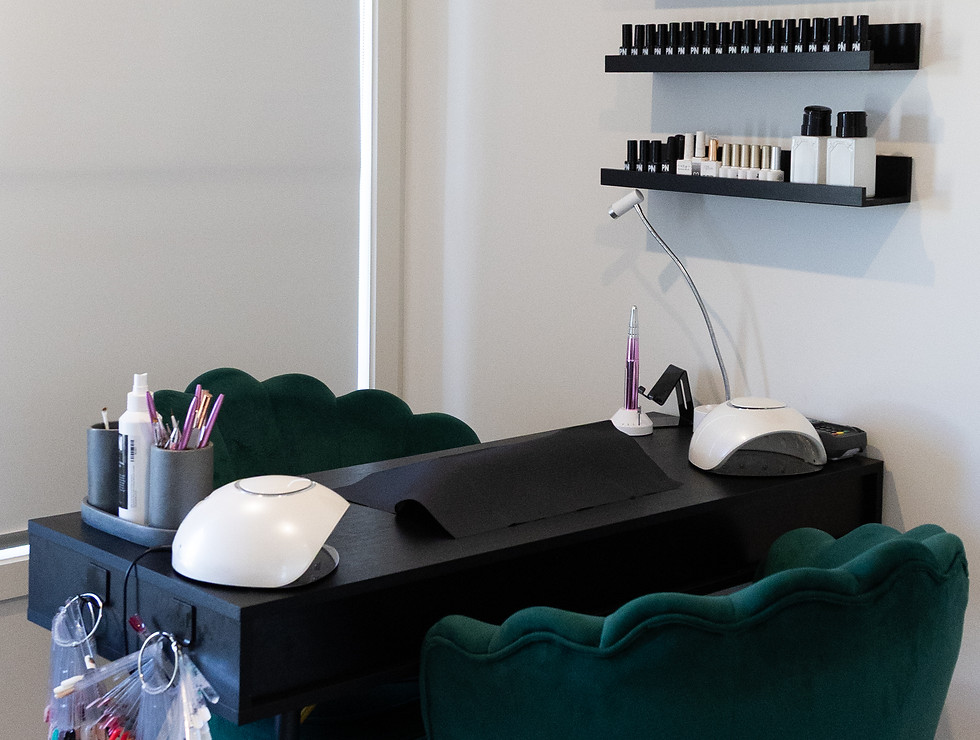 Nail desk with comfortable emerald green chairs, nail lamps and a large range of gel polishes.