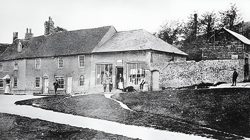 Red Elephant Siam, Thai restaurant, East Dean, Eastbourne, a photo of the site before the current building existed, when the green and surrounding land were part of an operational farm, with a high flint wall and horse stables standing where the restaurant now is.