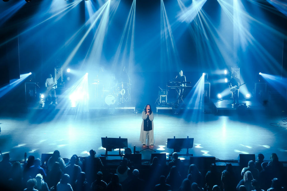 Concert stage with bright blue lights and performer.
