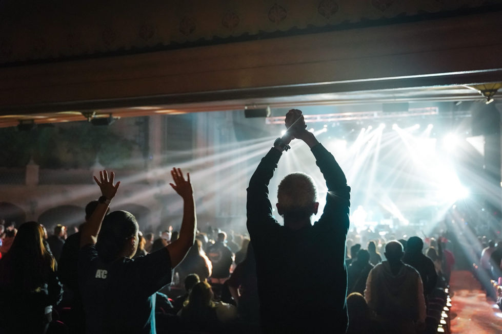 Audience cheering at a concert with bright lights.