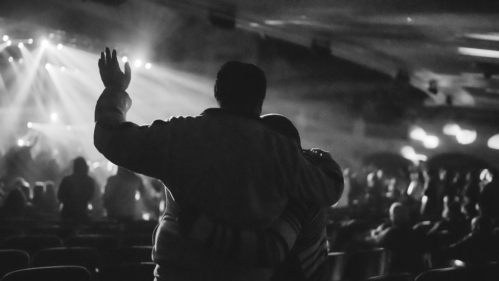 Silhouetted couple embracing at a concert.