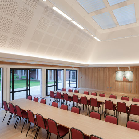Interior view of the New Dining Hall at Leckhampton, Corpus Christi College, University of Cambridge, designed by Haysom Ward Miller Architects, featuring oak wall panels, acoustic detailing, and natural light from skylights.