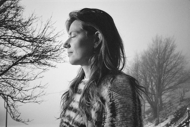 Black and white photograph of woman in striped sweater against a misty forest background