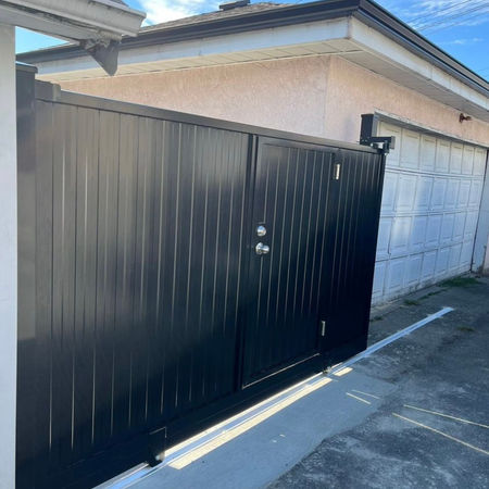 Black sliding gate with swing door inside in Vancouver