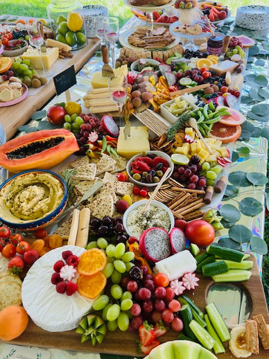 Outdoor grazing table filled with cheese, fresh fruits, dips, and crackers. Ideal for events in a relaxed, open setting.