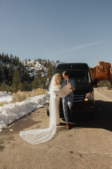 Adventure bride and groom standing in front of a travel van