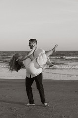 a husband holding and spinning his wife on the beach