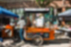Dominique interacting with a customer at the Zemi Coffee Cart during a busy outdoor market with local vendors.