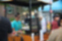 Dominique serving customers at the Zemi Coffee Cart, with guests browsing the menu at a busy outdoor daytime event.