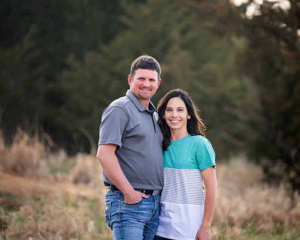 Mom and dad together posing for family portraits in open field on a summer Nebraska afternoon.